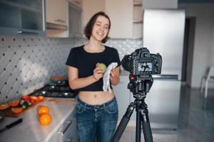 gewoon poseren voor de camera en wat eten maken van fruit. meisje in de moderne keuken thuis in haar weekendtijd in de ochtend foto