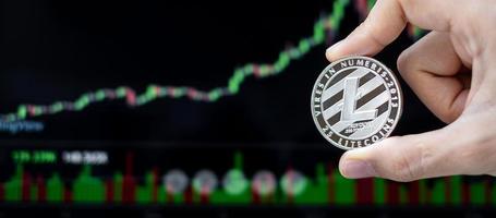 zilveren litecoin cryptocurrency-munt met kaarsgrafiekachtergrond, crypto is digitaal geld binnen het blockchain-netwerk, maakt gebruik van technologie en online internetuitwisseling. foto