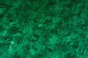 groene abstracte textuurachtergrond van smaragdgroen zeewater. bovenaanzicht van groen zeewater met uniek patroon. groene achtergrond. zeewater golfoppervlak aan de kust. turquoise water op ondiepe zee. foto