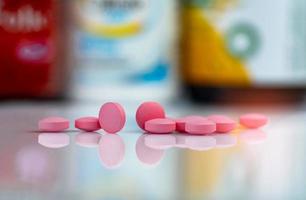 roze tablettenpillen op onscherpe achtergrond van medicijndoos en medicijnfles. vitamines en supplementen tabletten. apotheek drogisterij. farmaceutische producten. gezondheidszorg en farmacie. medicatie verzoenen. foto