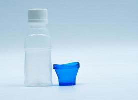 steriele ooglotion in witte plastic fles met blauw oogbad en kopieerruimte en blanco label. oogspoeling na contact met vervuiling van de omgeving of na het zwemmen in chloor verontreinigd zwembad. foto