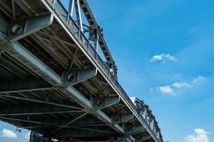 stalen brugstructuur tegen blauwe lucht en witte wolken. ijzeren brug technische constructie. sterke en sterkte metalen brug. weg brug architectuur. infrastructuur. foto