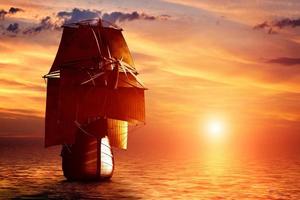 oud piratenschip dat bij zonsondergang op de oceaan vaart foto