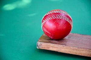 close-up oude cricketsportuitrusting op groene vloer, oude leren bal, houten vleermuis, zachte en selectieve focus, traditionele cricketsportliefhebbers over het hele wereldconcept. foto