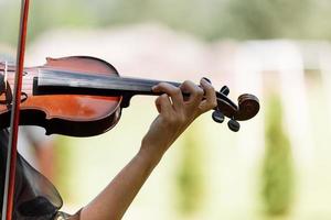 de hand van een violist. muzikant die optreedt op een buitenhuwelijk. krul met viool nek close-up. de acteur treedt op op een feest. muziekinstrument foto