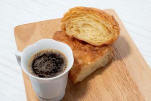 ontbijt eten koffie en croissant op witte houten tafel. foto