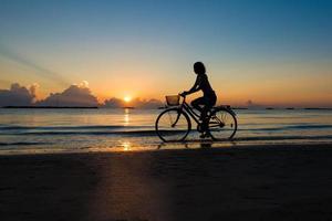meisje fietsen in de zee tijdens zonsopgang foto