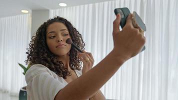 jonge latijnse vrouw die haar smartphone als spiegel gebruikt om het goed te maken. foto