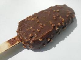 chocolade-ijssticks gegarneerd met notenkruimels. effen witte achtergrond. selectieve aandacht. foto