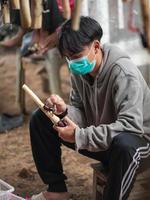 chiang mai, thailand, 2021 - Thaise mannelijke tiener die de wreedheid van de siamese neushoornkever of vechtkever test alvorens te kopen. foto