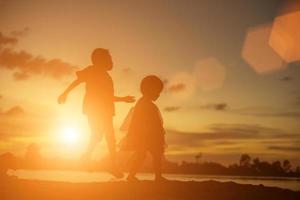 silhouetten van moeder en dochtertje wandelen bij zonsondergang foto