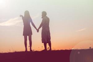 silhouet van een man en vrouw hand in hand met elkaar, samen wandelen. foto