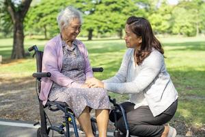 verzorger hulp en zorg Aziatische senior of oudere oude dame vrouw patiënt zittend en gelukkig op rolstoel in park, gezond sterk medisch concept. foto