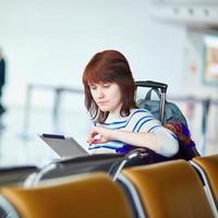 jonge passagier op de luchthaven, met behulp van haar tablet