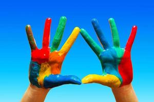 geschilderde handen, kleurrijk plezier. blauwe lucht foto