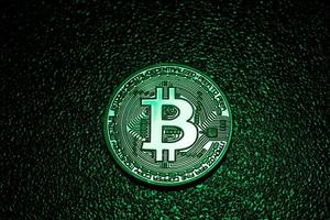een munt met bitcoin-logo in een groene verlichting. foto