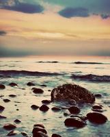 dramatische zonsopgang op een rotsachtig strand. retro, vintage foto