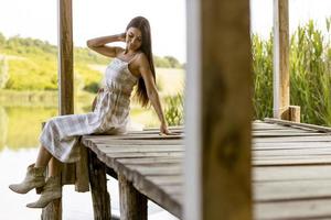 jonge vrouw ontspannen op de houten pier aan het rustige meer foto