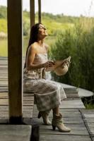 jonge vrouw ontspannen op de houten pier aan het rustige meer foto
