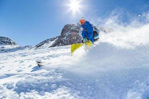 skiër skiën bergafwaarts in hoge bergen foto