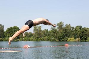 man springen van duikplank bij zwembad foto