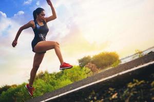 silhouet van jonge vrouw die sprinten op de weg loopt. fit runner fitness runner tijdens outdoor training met zonsondergang achtergrond. foto