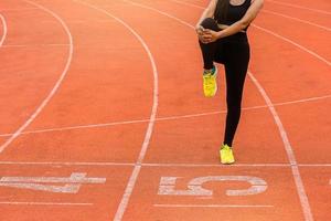 jonge vrouw runner warming-up op de renbaan. fit runner workout, haar spieren strekken en opwarmen op het circuit. foto