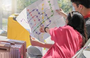 jonge aziatische paarreiziger die beschermend gezichtsmasker draagt en bespreekt om samen een reis te plannen met een mock-up metro transitkaart. selectieve focus, lichteffect. foto