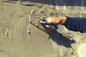 hand van arbeider die cement op muur pleistert foto