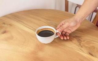 zwarte koffiekop in de hand op houten tafel foto