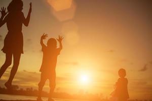 silhouetten van moeder en dochtertje wandelen bij zonsondergang foto