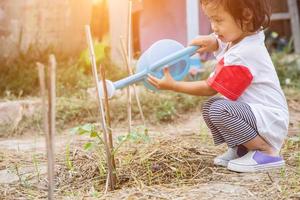 kleine meid die boom water geeft met gieter foto