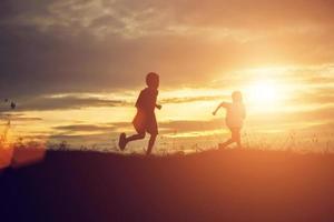 silhouet van een gelukkige kinderen en een gelukkige zonsondergang foto