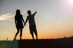 silhouet van een man en vrouw hand in hand met elkaar, samen wandelen. foto