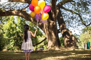 klein meisje met ballonnen in een veld foto