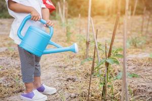 kleine meid die boom water geeft met gieter foto