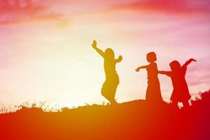 silhouet van een gelukkige kinderen en een gelukkige zonsondergang foto