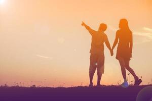 silhouet van een man en vrouw hand in hand met elkaar, samen wandelen. foto