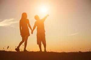 silhouet van een man en vrouw hand in hand met elkaar, samen wandelen. foto