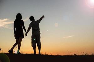 silhouet van een man en vrouw hand in hand met elkaar, samen wandelen. foto