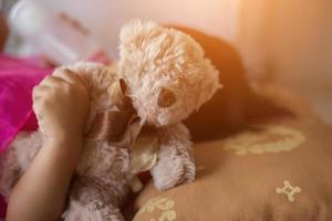 gelukkig klein meisje in pet spelen met teddybeer in zomerpark foto