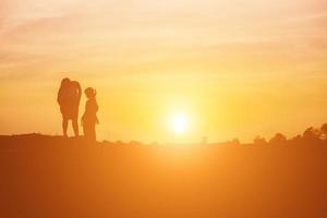 moeder moedigde haar dochter bij zonsondergang uit de schaduw aan. foto