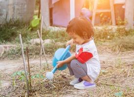 kleine meid die boom water geeft met gieter foto