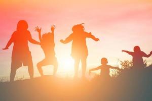 silhouet van een gelukkige kinderen en een gelukkige zonsondergang foto