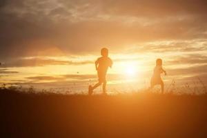 silhouet van een gelukkige kinderen en een gelukkige zonsondergang foto