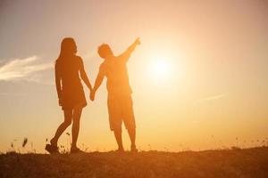 silhouet van een man en vrouw hand in hand met elkaar, samen wandelen. foto