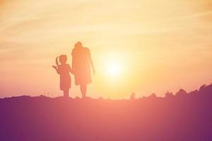 moeder moedigde haar dochter bij zonsondergang uit de schaduw aan. foto