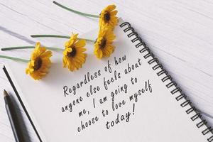 motiverende citaat op notitieboek met zonnebloemen op houten bureau. foto