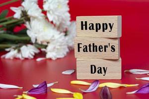 tekst op houten kubus en met bloem op rode achtergrond - gelukkige vaderdag foto
