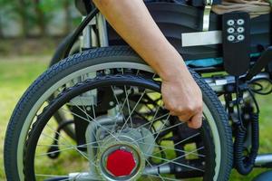 Aziatische oudere vrouw handicap patiënt zittend op elektrische rolstoel in park, medisch concept. foto